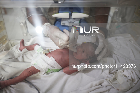 A doctor is checking a baby lying in an incubator at the newborns' intensive care unit at the International Medical Corps field hospital, am...