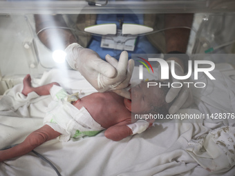 A doctor is checking a baby lying in an incubator at the newborns' intensive care unit at the International Medical Corps field hospital, am...