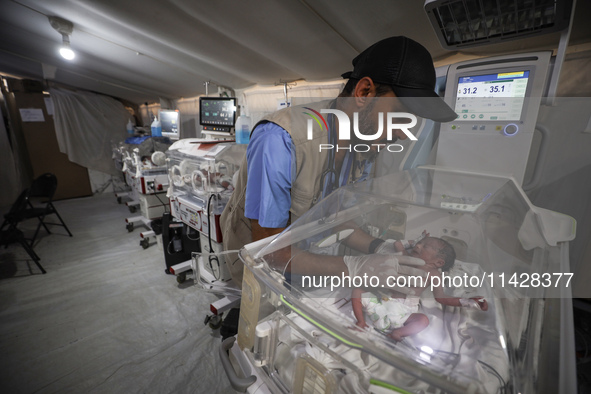 A doctor is checking a baby lying in an incubator at the newborns' intensive care unit at the International Medical Corps field hospital, am...