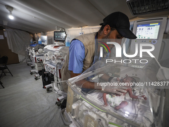 A doctor is checking a baby lying in an incubator at the newborns' intensive care unit at the International Medical Corps field hospital, am...