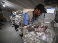 A doctor is checking a baby lying in an incubator at the newborns' intensive care unit at the International Medical Corps field hospital, am...