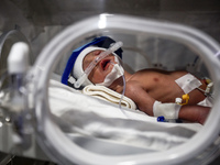 A Palestinian baby is lying in an incubator at the newborns' intensive care unit at the International Medical Corps field hospital, amid the...