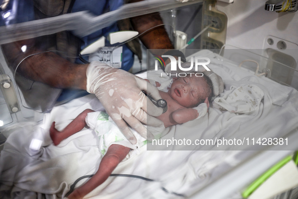 A doctor is checking a baby lying in an incubator at the newborns' intensive care unit at the International Medical Corps field hospital, am...