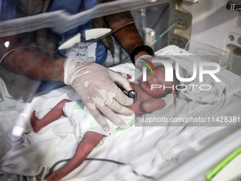 A doctor is checking a baby lying in an incubator at the newborns' intensive care unit at the International Medical Corps field hospital, am...