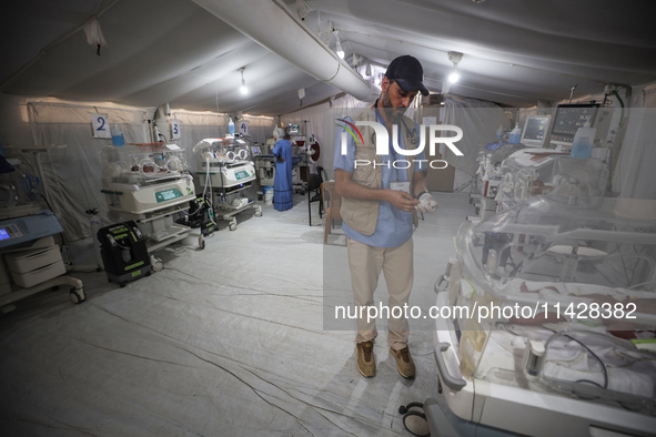 A doctor is checking a baby lying in an incubator at the newborns' intensive care unit at the International Medical Corps field hospital, am...