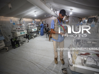 A doctor is checking a baby lying in an incubator at the newborns' intensive care unit at the International Medical Corps field hospital, am...