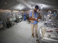 A doctor is checking a baby lying in an incubator at the newborns' intensive care unit at the International Medical Corps field hospital, am...