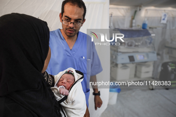 A doctor is checking a baby lying in an incubator at the newborns' intensive care unit at the International Medical Corps field hospital, am...