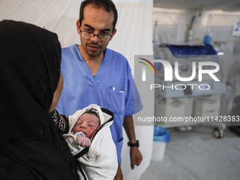 A doctor is checking a baby lying in an incubator at the newborns' intensive care unit at the International Medical Corps field hospital, am...