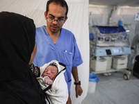 A doctor is checking a baby lying in an incubator at the newborns' intensive care unit at the International Medical Corps field hospital, am...