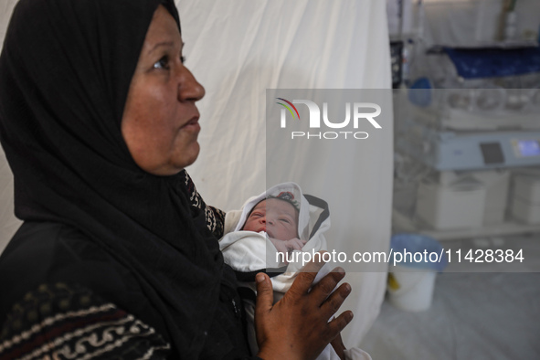 A doctor is checking a baby lying in an incubator at the newborns' intensive care unit at the International Medical Corps field hospital, am...