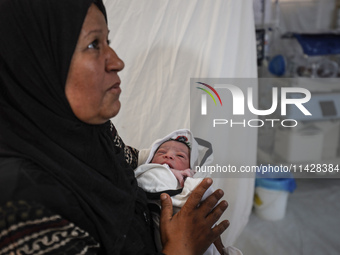 A doctor is checking a baby lying in an incubator at the newborns' intensive care unit at the International Medical Corps field hospital, am...