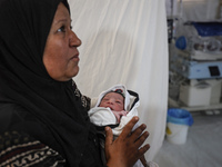 A doctor is checking a baby lying in an incubator at the newborns' intensive care unit at the International Medical Corps field hospital, am...