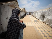 A displaced Palestinian mother is holding her baby at the International Medical Corps field hospital, amid the Israel-Hamas conflict, in Dei...