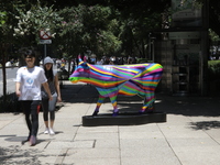 Persons are walking next to a fiberglass cow painted by an artist during the inauguration of the 'Cowparade Mexico 2024' on Avenida Reforma...