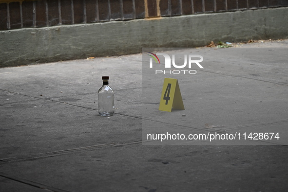 An evidence marker is being placed at the crime scene where a shell casing is being discovered next to a bottle of liquor following an overn...