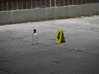 An evidence marker is being placed at the crime scene where a shell casing is being discovered next to a bottle of liquor following an overn...