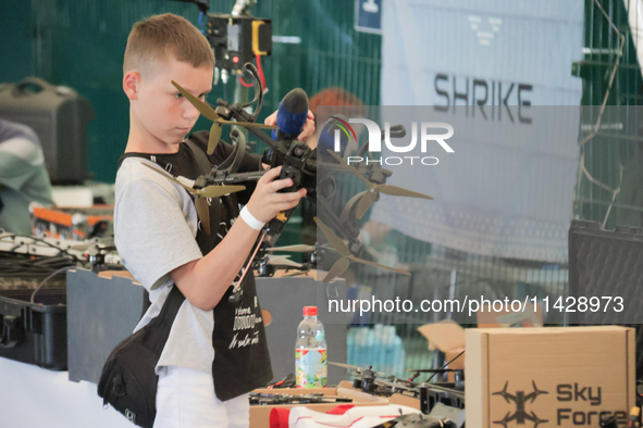 A boy is looking at a drone on display during the 2nd Drone Racing Tournament by the Federation of Military and Technological Sports of Ukra...