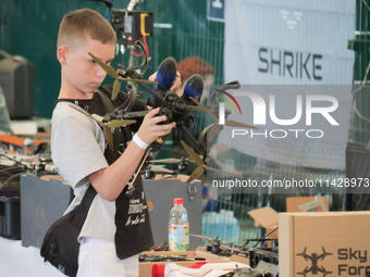 A boy is looking at a drone on display during the 2nd Drone Racing Tournament by the Federation of Military and Technological Sports of Ukra...