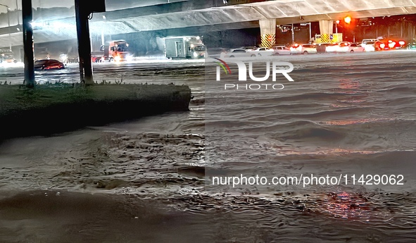 Vehicles are driving in a flooded area after heavy rain in Zhengzhou, China, on July 22, 2024. 