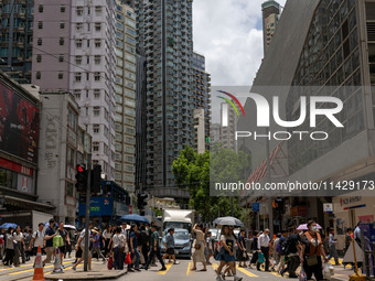 People are crossing the road in Hong Kong, China, on July 22, 2024. (