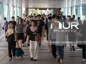 People are walking on a footbridge in Hong Kong, on July 22, 2024. (