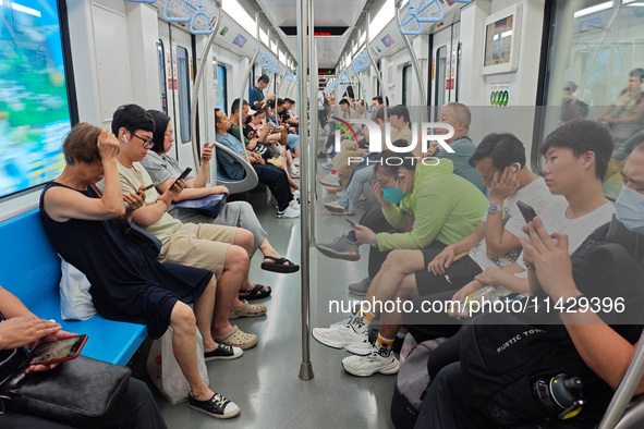 Passengers are looking at their mobile phones during the operation of Metro Line 8 in Shanghai, China, on July 23, 2024. 