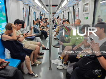 Passengers are looking at their mobile phones during the operation of Metro Line 8 in Shanghai, China, on July 23, 2024. (