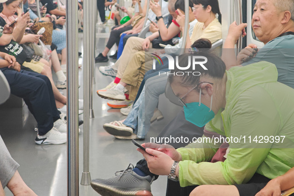 Passengers are looking at their mobile phones during the operation of Metro Line 8 in Shanghai, China, on July 23, 2024. 