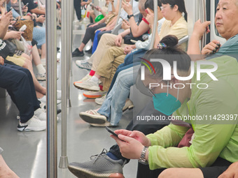 Passengers are looking at their mobile phones during the operation of Metro Line 8 in Shanghai, China, on July 23, 2024. (