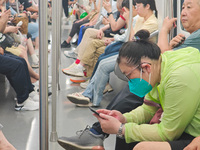 Passengers are looking at their mobile phones during the operation of Metro Line 8 in Shanghai, China, on July 23, 2024. (