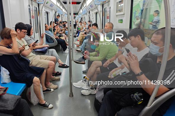 Passengers are looking at their mobile phones during the operation of Metro Line 8 in Shanghai, China, on July 23, 2024. 