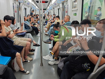 Passengers are looking at their mobile phones during the operation of Metro Line 8 in Shanghai, China, on July 23, 2024. (