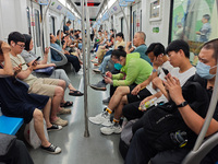 Passengers are looking at their mobile phones during the operation of Metro Line 8 in Shanghai, China, on July 23, 2024. (