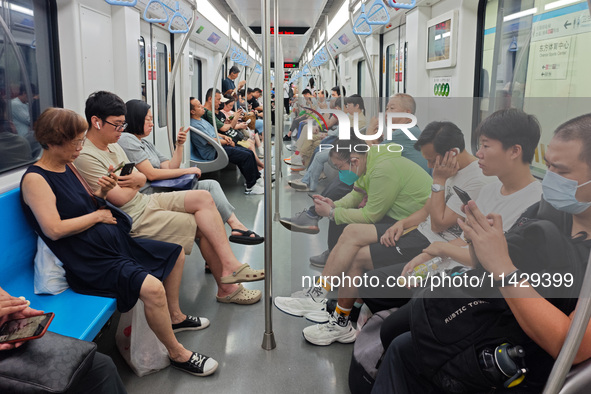 Passengers are looking at their mobile phones during the operation of Metro Line 8 in Shanghai, China, on July 23, 2024. 