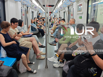 Passengers are looking at their mobile phones during the operation of Metro Line 8 in Shanghai, China, on July 23, 2024. (