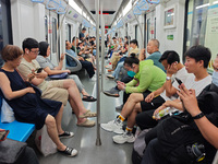 Passengers are looking at their mobile phones during the operation of Metro Line 8 in Shanghai, China, on July 23, 2024. (