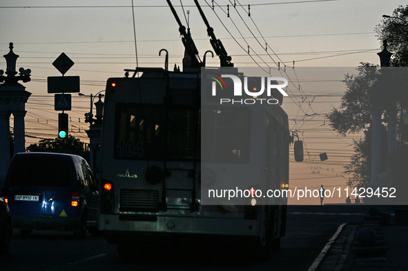 A trolleybus is being seen on the dark screen at night as the city is switching off street lights due to power shortages in the region and t...