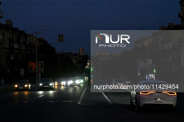 Cars are on the road at night as the city is switching off street lights due to power shortages in the region and to save electricity for re...