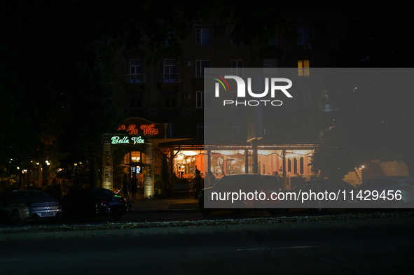 An illuminated restaurant is being seen at night as the city is switching off street lights due to power shortages in the region and to save...