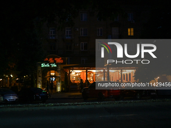 An illuminated restaurant is being seen at night as the city is switching off street lights due to power shortages in the region and to save...