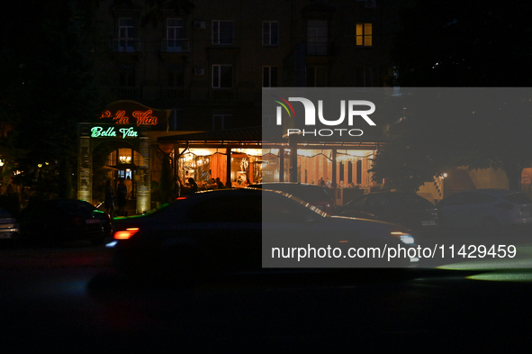 A car is moving past an illuminated restaurant at night as the city is switching off street lights due to power shortages in the region and...