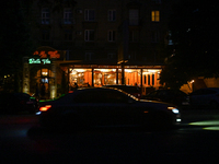 A car is moving past an illuminated restaurant at night as the city is switching off street lights due to power shortages in the region and...