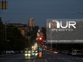 Cars are on the road at night as the city is switching off street lights due to power shortages in the region and to save electricity for re...