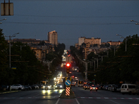 Cars are on the road at night as the city is switching off street lights due to power shortages in the region and to save electricity for re...