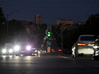 Cars are on the road at night as the city is switching off street lights due to power shortages in the region and to save electricity for re...