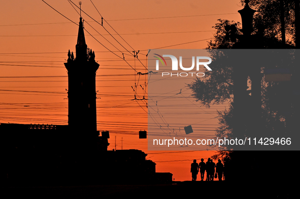 The silhouettes of people are being seen at sunset as the city is switching off street lights due to power shortages in the region and to sa...