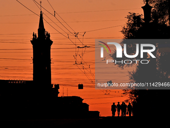 The silhouettes of people are being seen at sunset as the city is switching off street lights due to power shortages in the region and to sa...