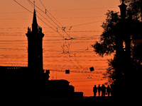 The silhouettes of people are being seen at sunset as the city is switching off street lights due to power shortages in the region and to sa...