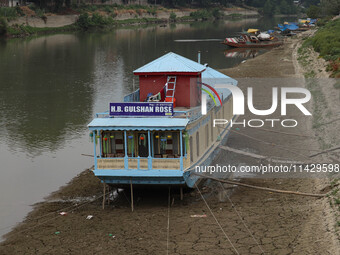 Owners are fixing wooden logs at the bottom to keep the balance of the houseboat on the dry beds of river Jhelum, as the dry spell is contin...